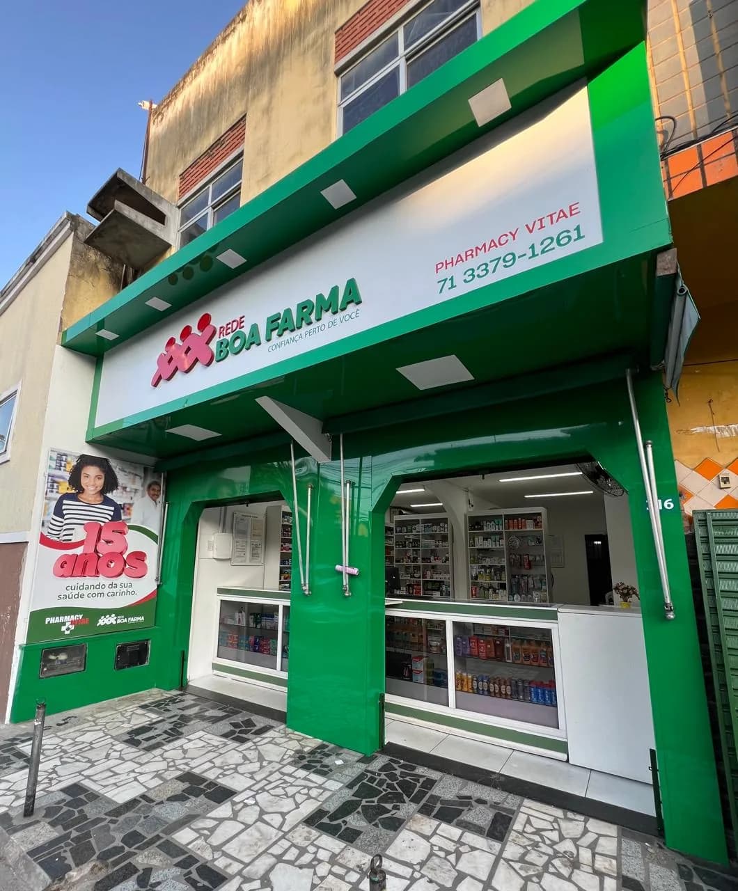 Fachada verde de farmácia com identificação em letras e acabamento de comunicação visual.