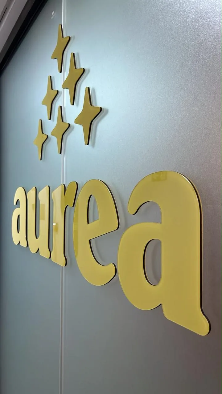 Detalhe de letras douradas em relevo e cinco emblemas aplicados à parede.