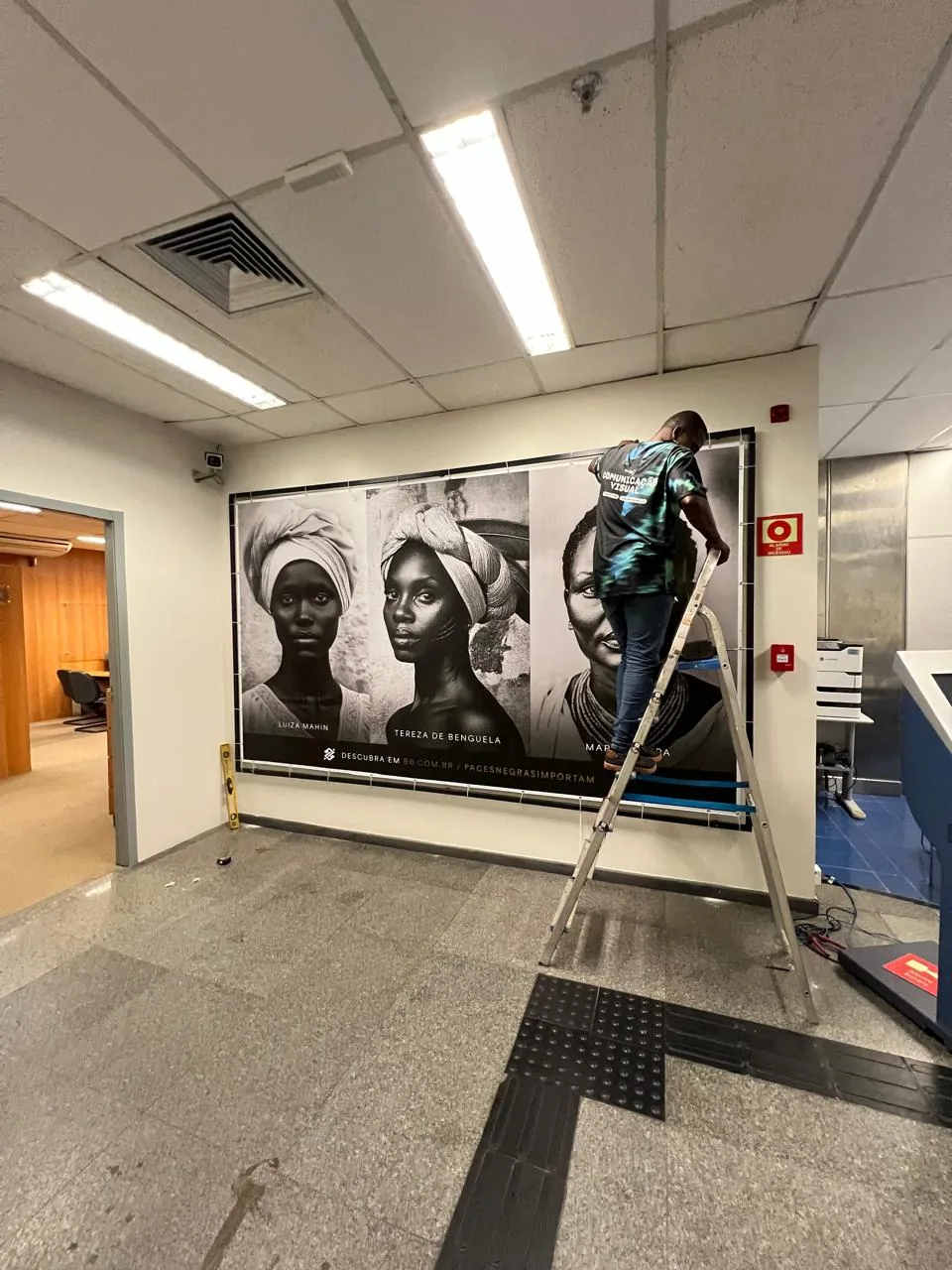 Painel fotográfico em preto e branco montado em estrutura para exposição.