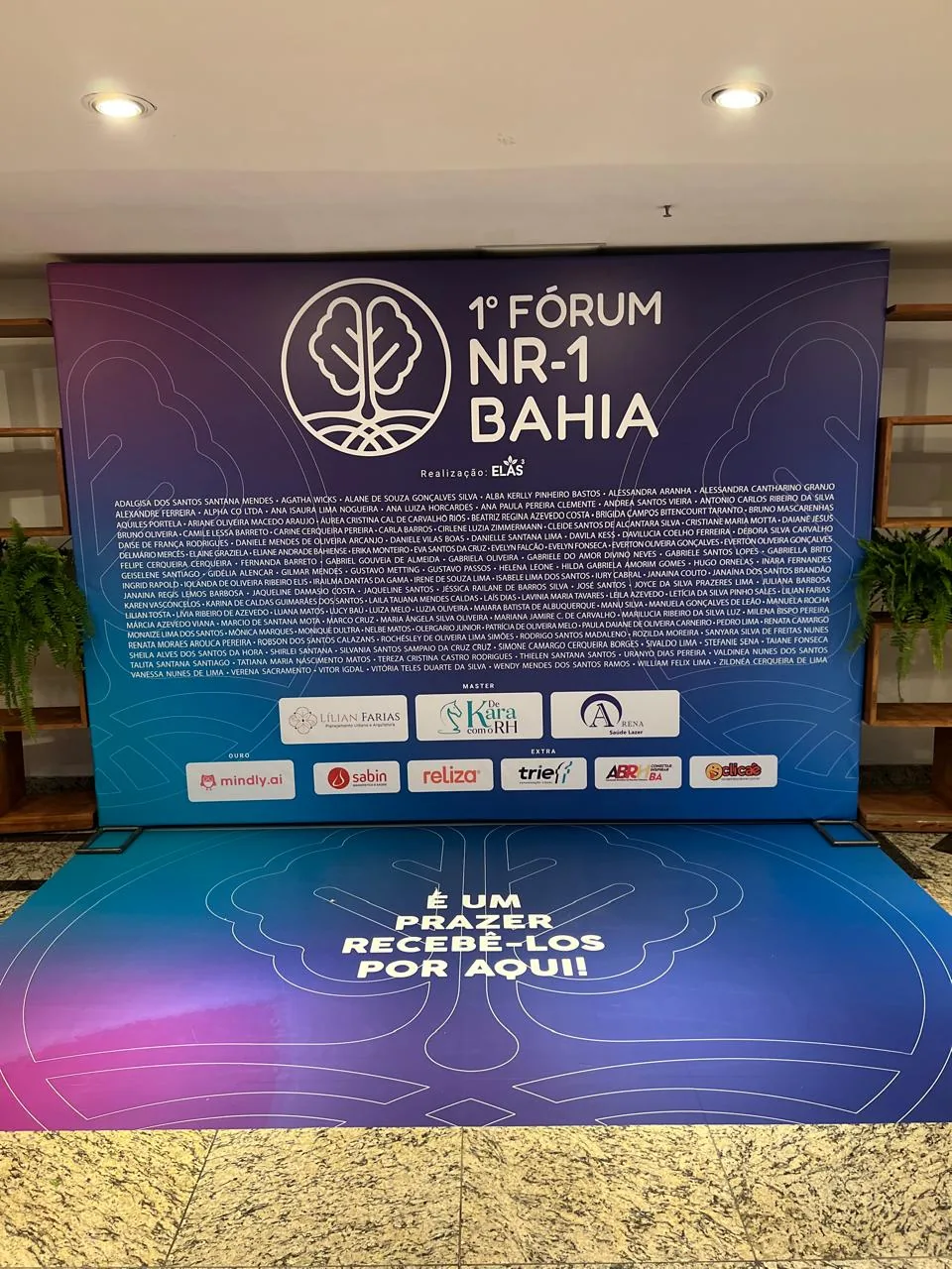 Comunicação visual do Fórum NR-1 Bahia em painéis de evento e área de convivência.