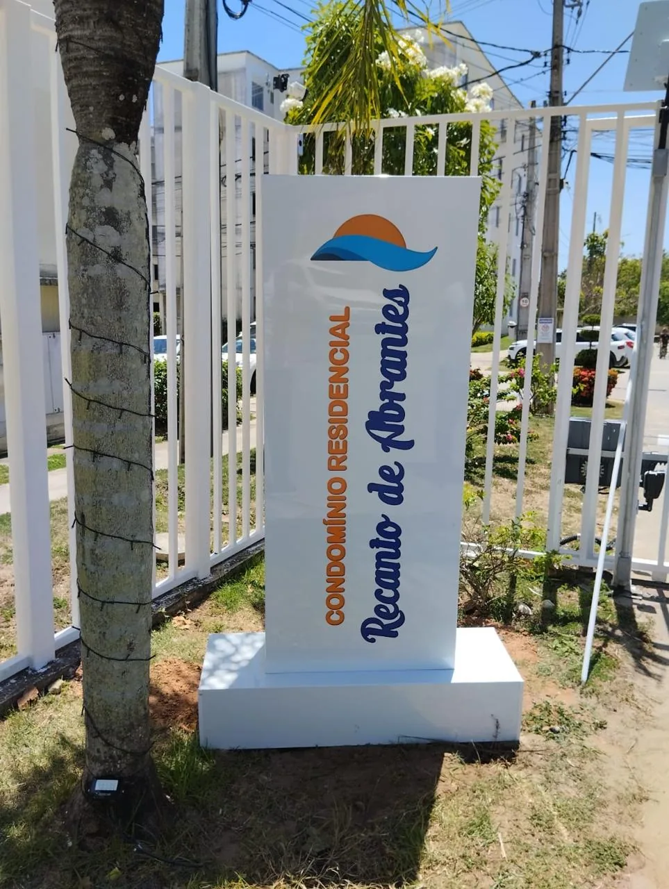 Totem branco de identificação institucional instalado em área externa.
